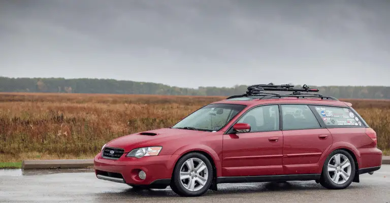 2005 subaru outback in a field under a clouded sky